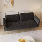 Canapé en velours noir orné de clous décoratifs et accompagné d'un coussin assorti.